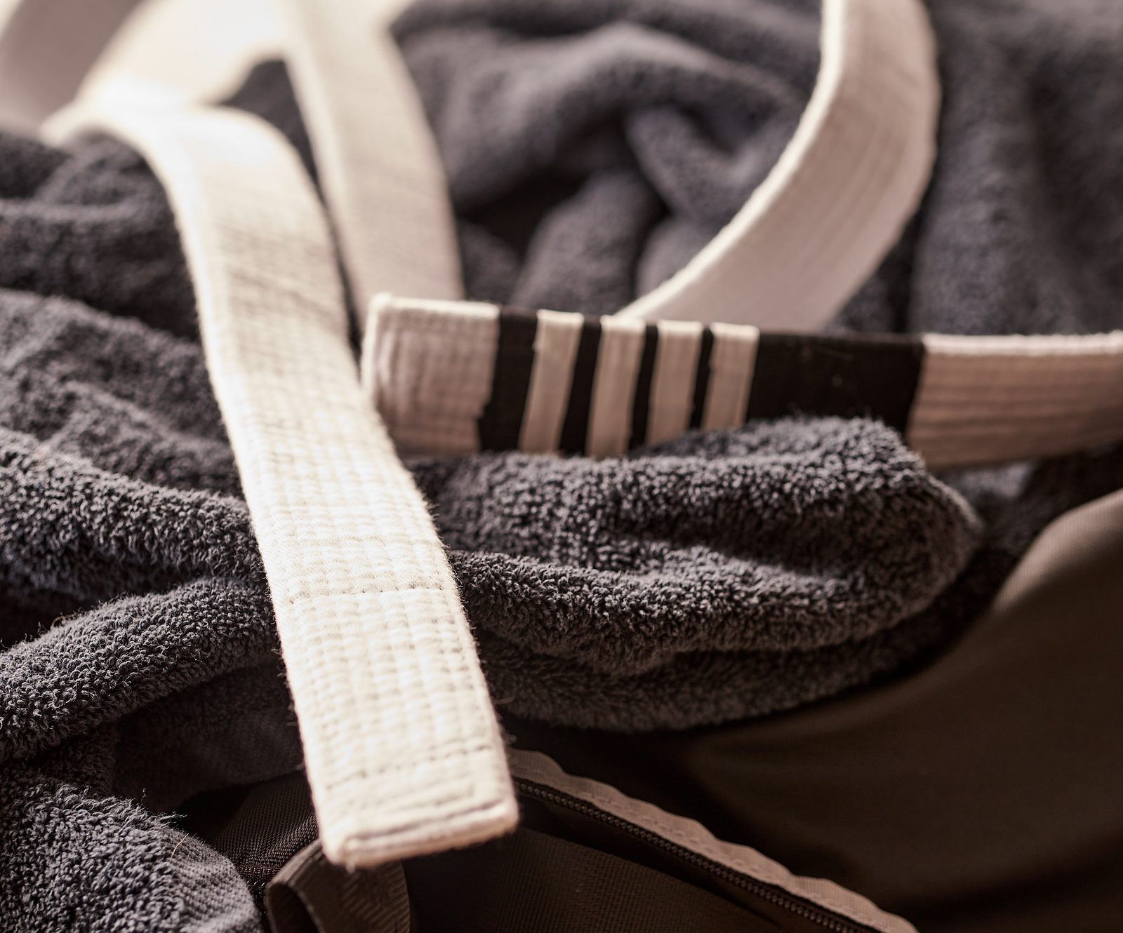 A belt draped over folded towels and a training bag.