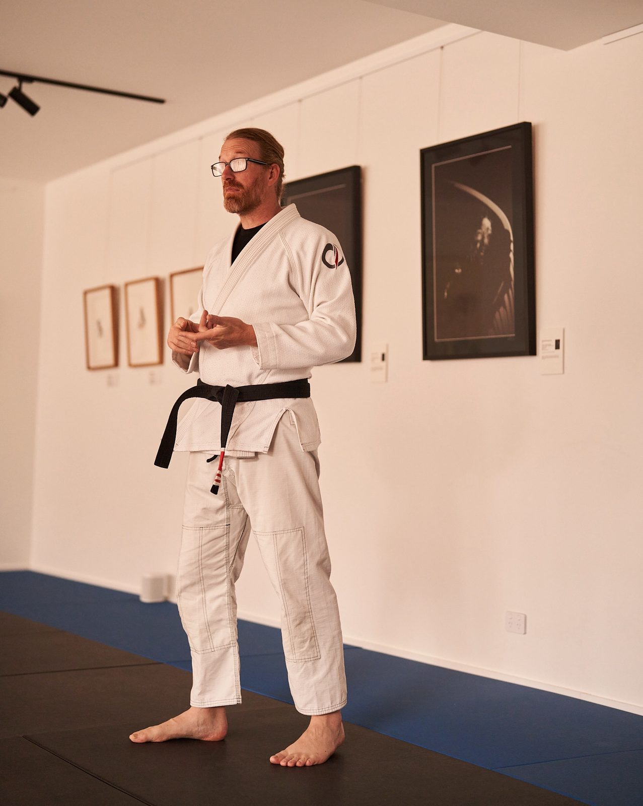The head coach talks the class through a technique beside the studio's gallery wall.