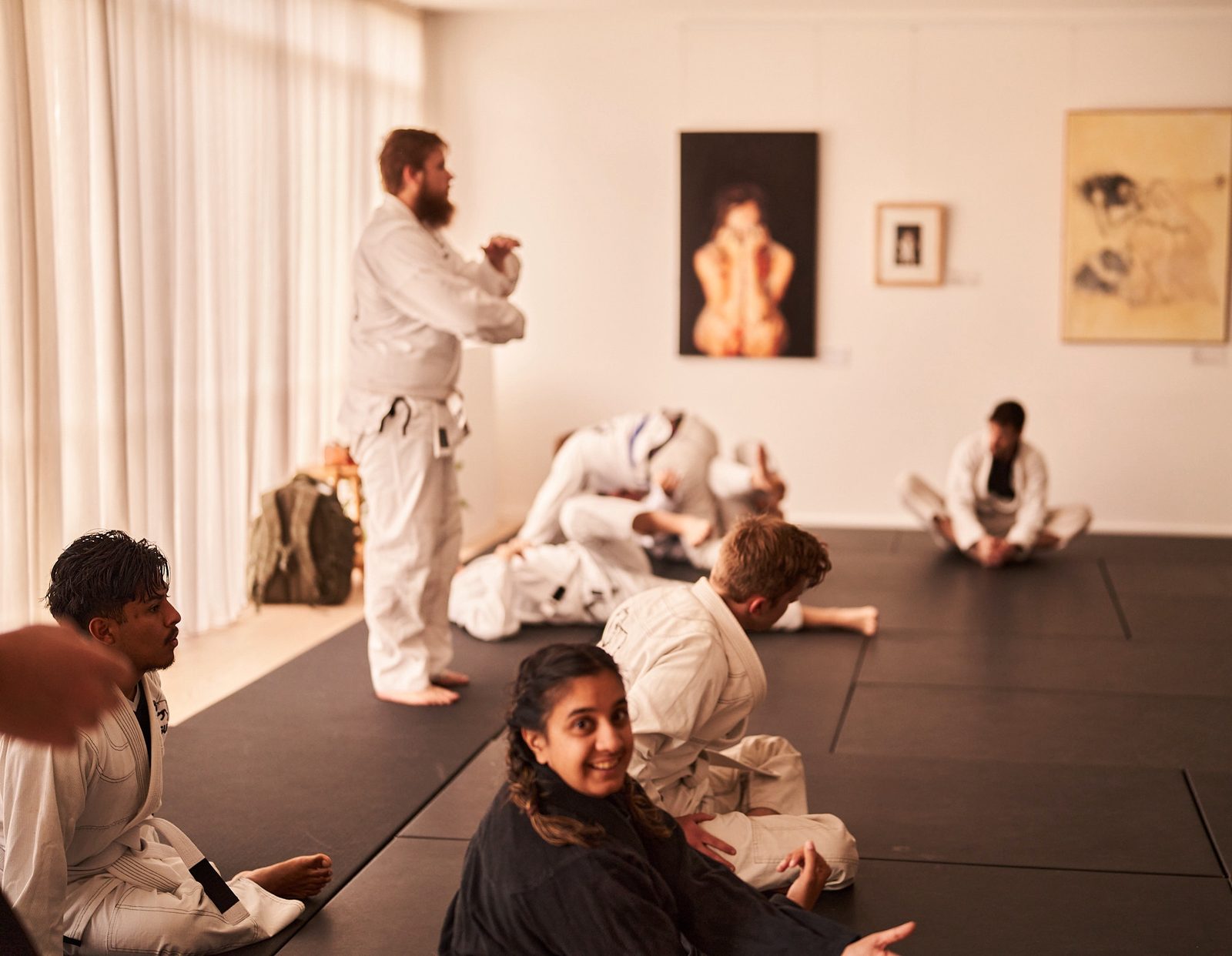 A student smiles over her shoulder as the instructor demonstrates a grip to the class.